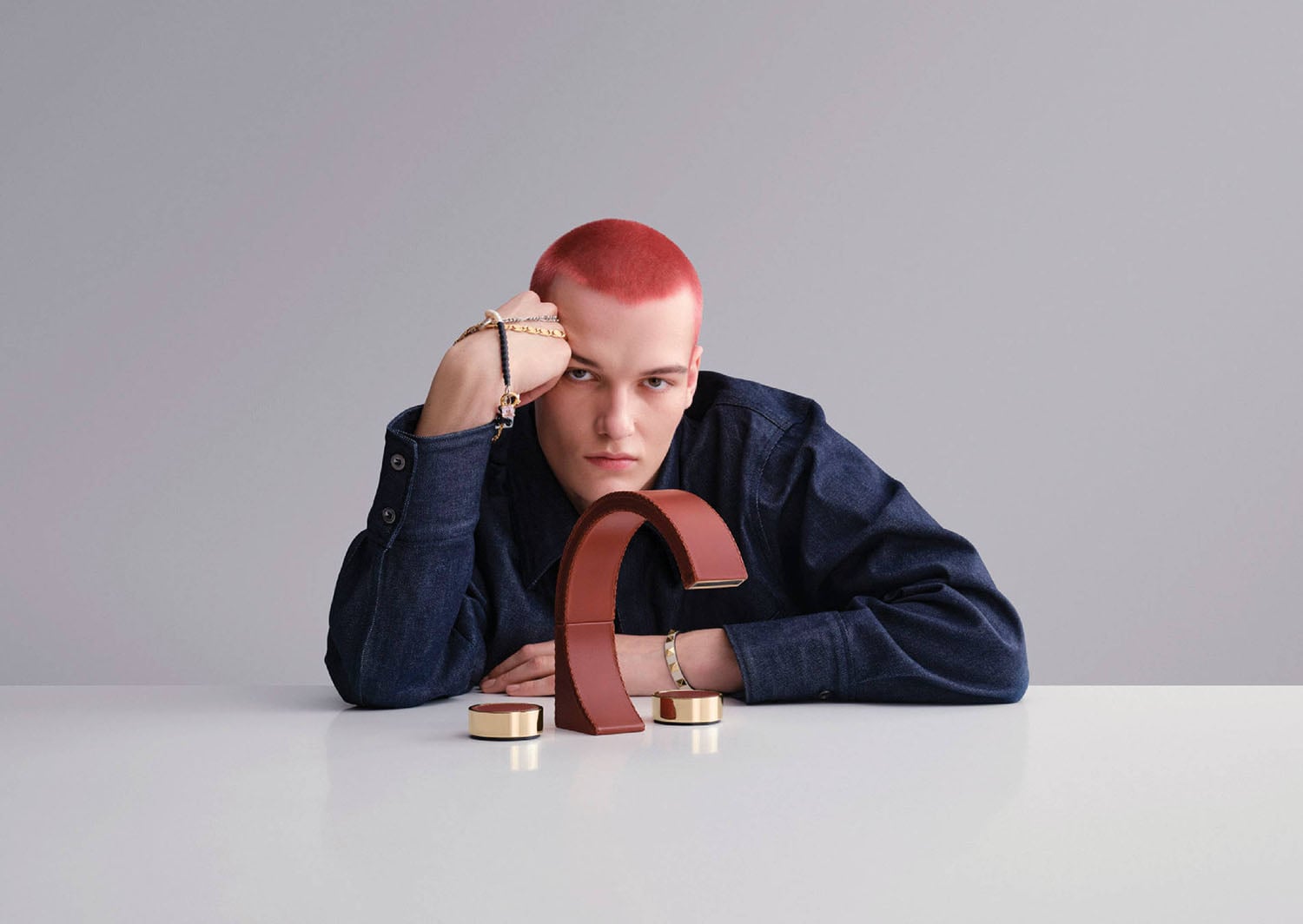 A woman with red hair and a blue jacket leaning on a table.