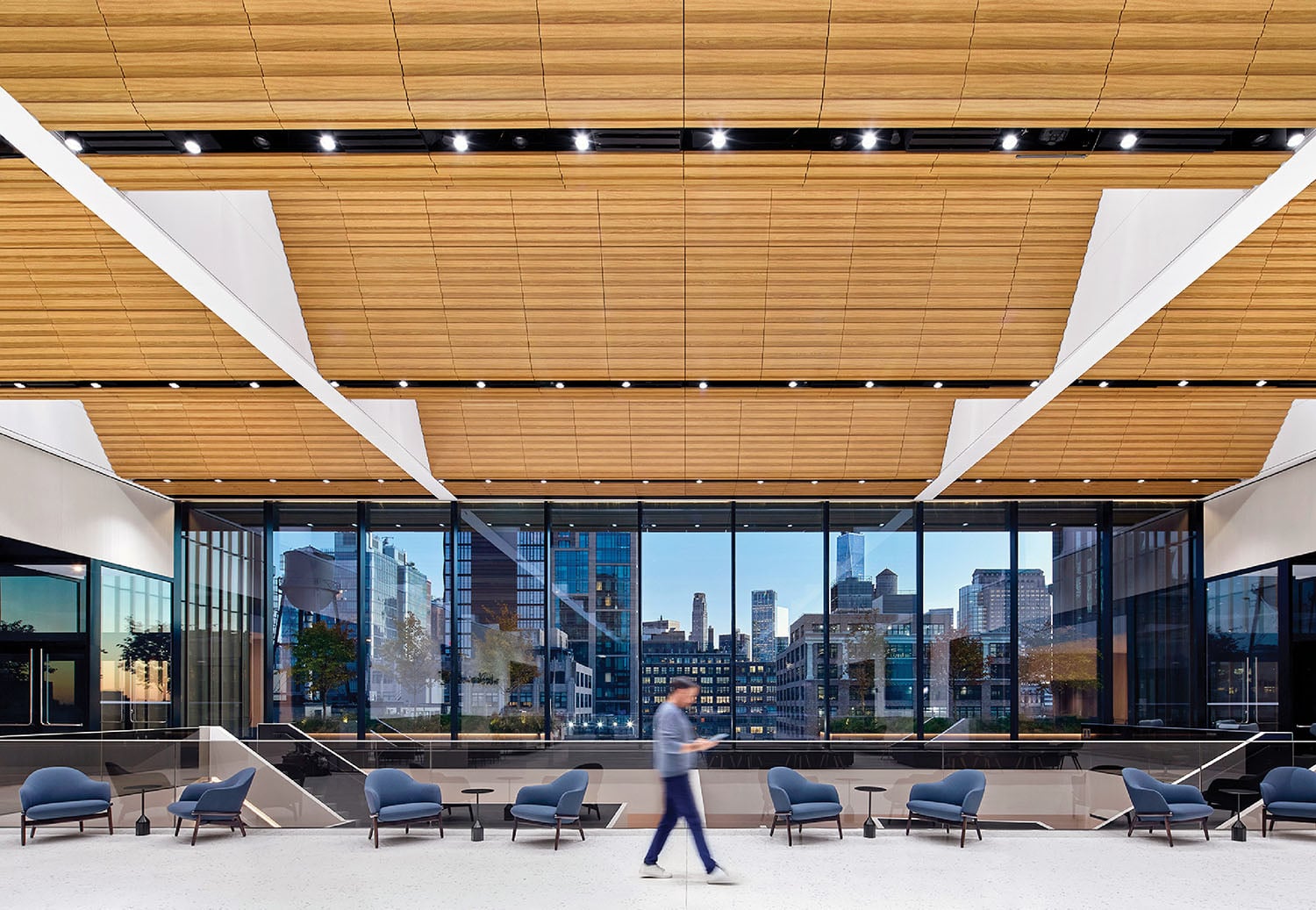 A man walking through a lobby with chairs.