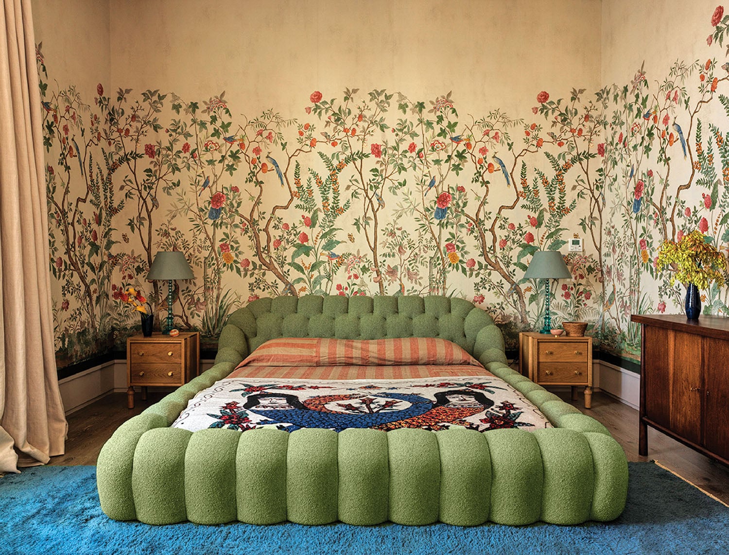 A bedroom with a bed and a green ottoman.