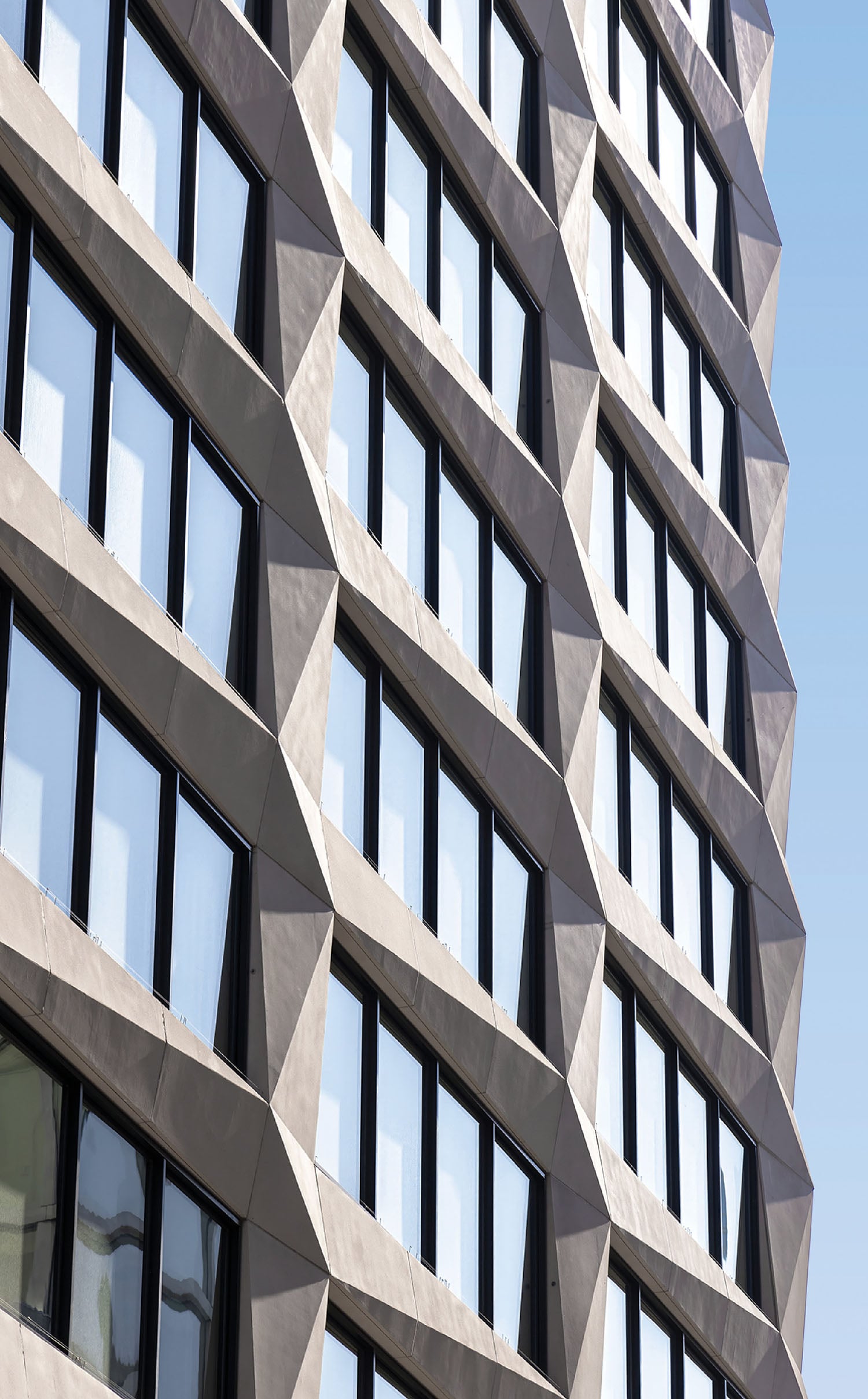 A tall building with many windows and a sky.