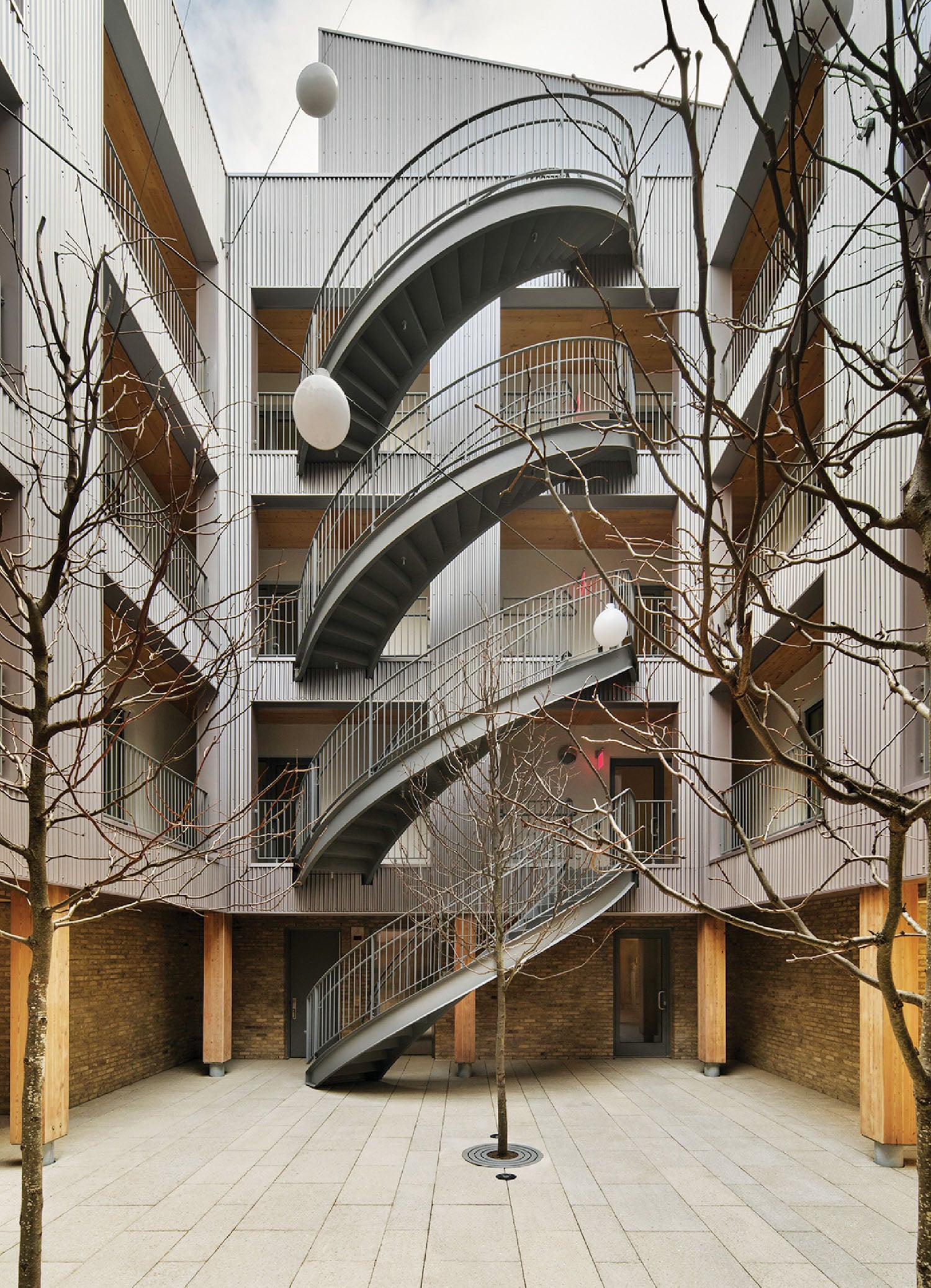 A spiral staircase in a courtyard with trees.