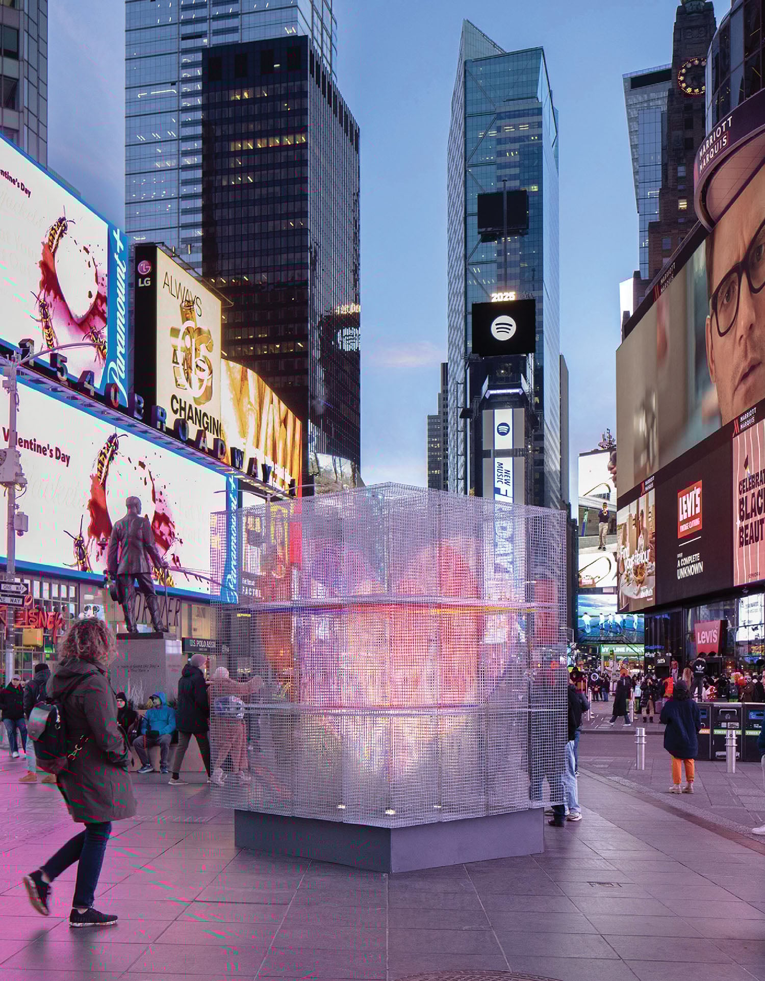 A man walking past a water fountain in a city.