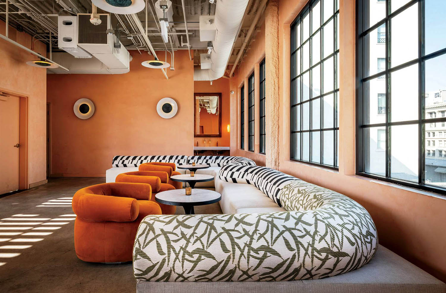 A room with orange chairs and a large round ottoman.