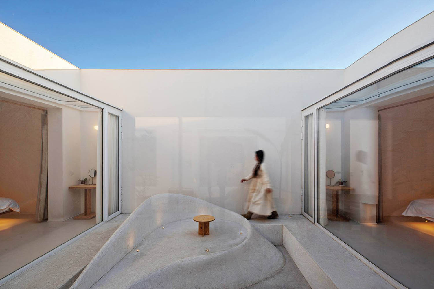 A woman walking through a room with a bed.