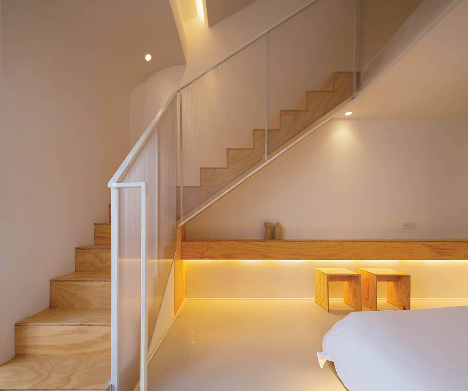 A bed sitting under a staircase in a bedroom.
