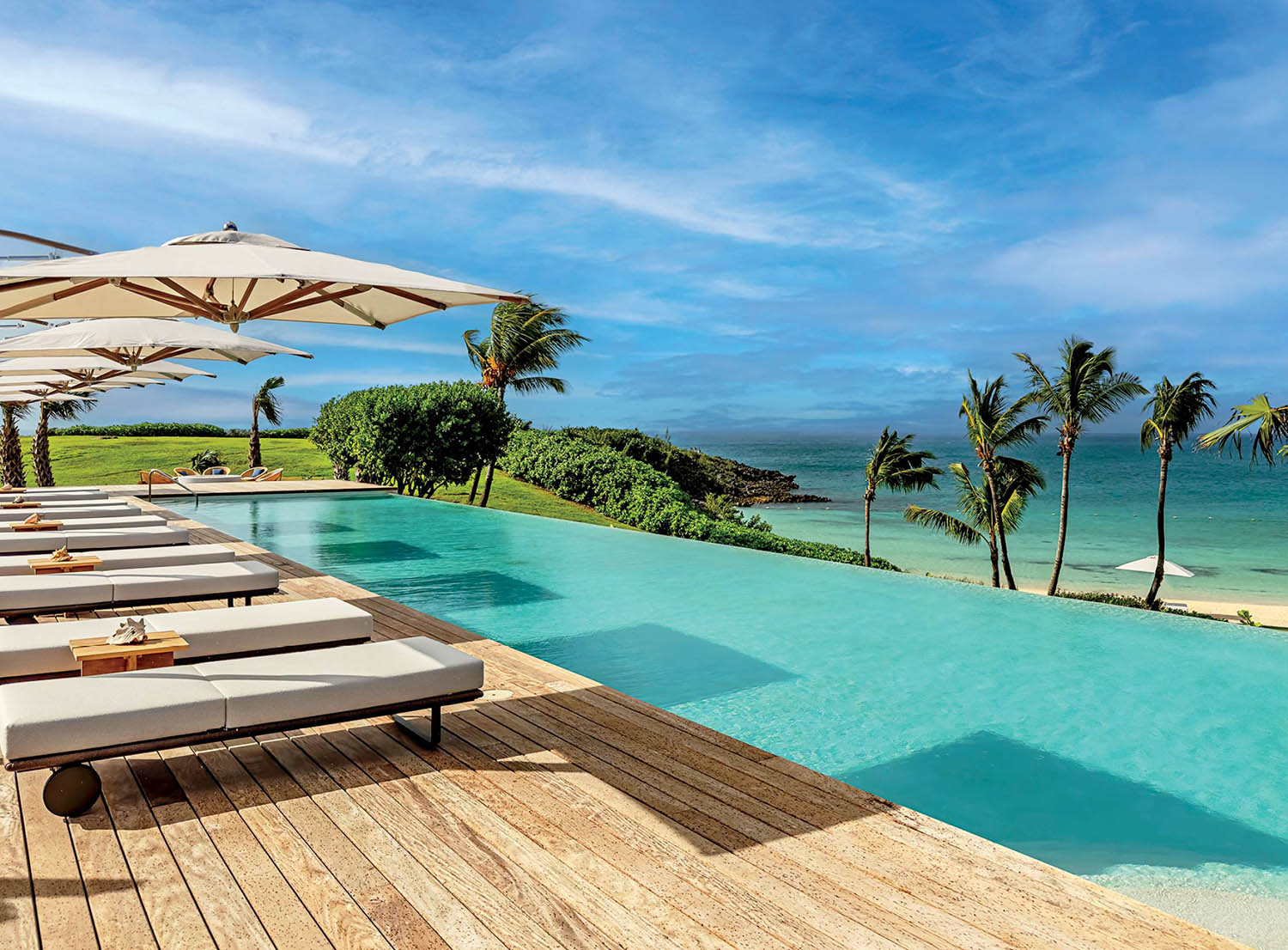 A wooden deck with lounge chairs and umbrellas.
