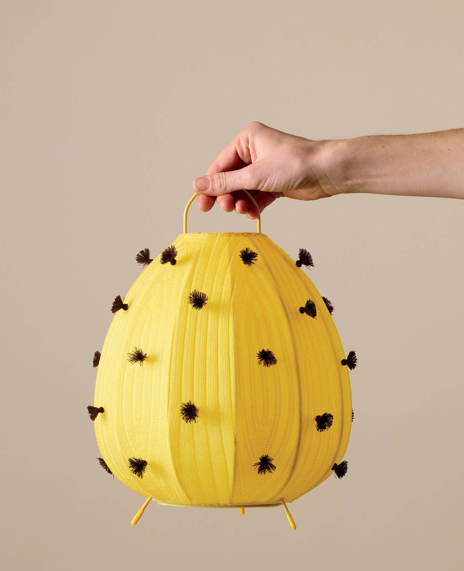 A hand holding a yellow pinata with black spots.