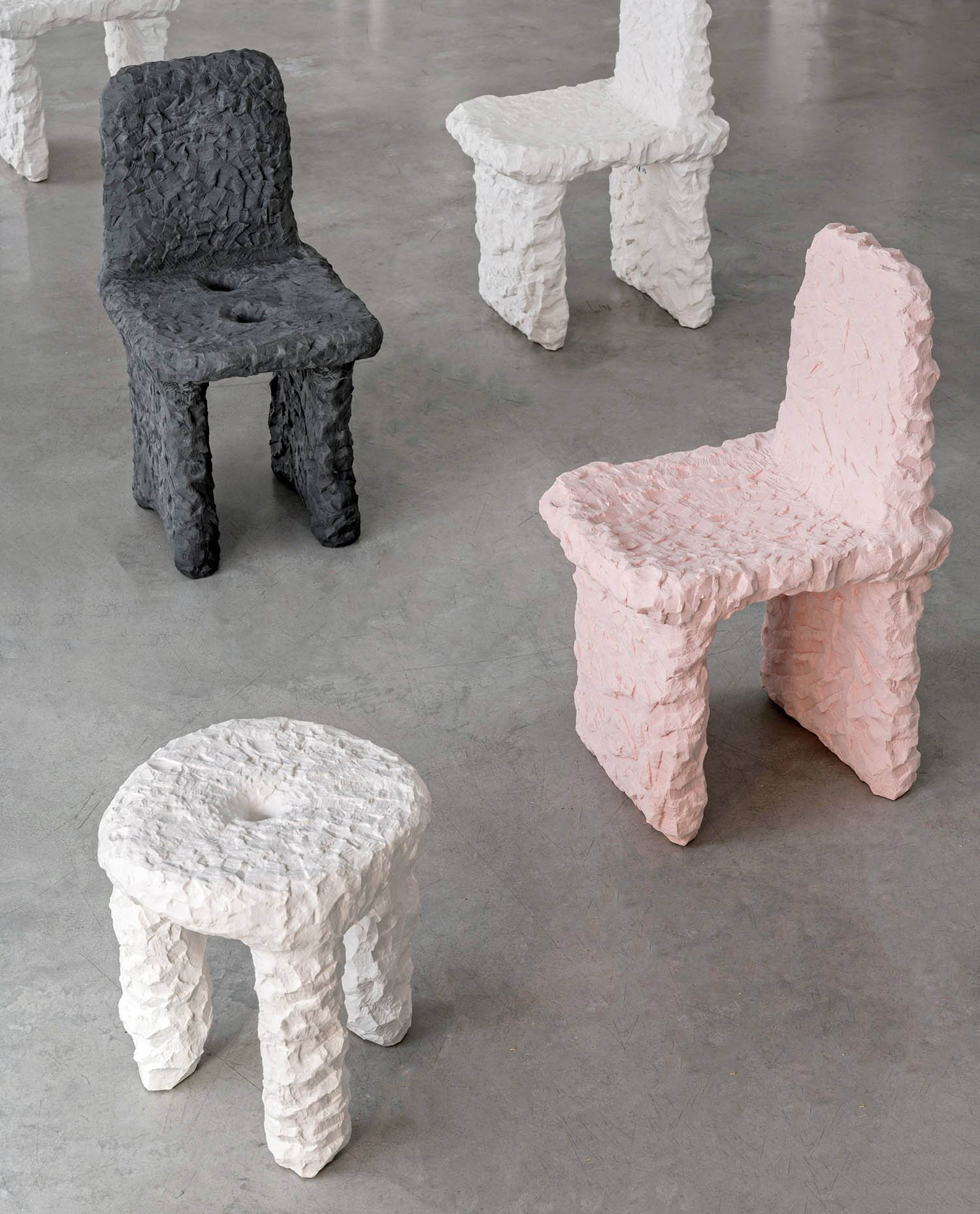 A group of three chairs sitting on top of a cement floor.