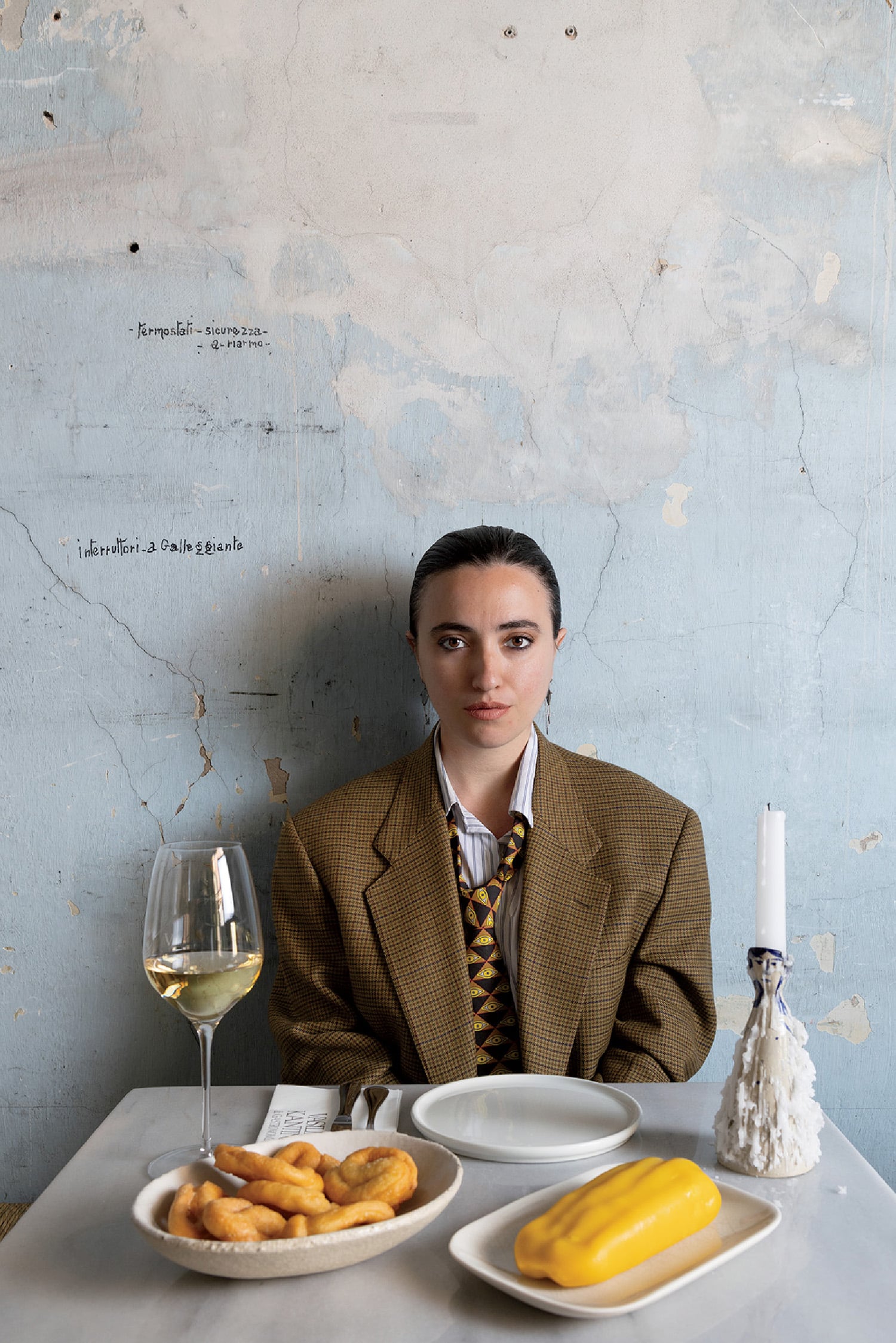 A woman sitting at a table with a plate of food and a glass of win