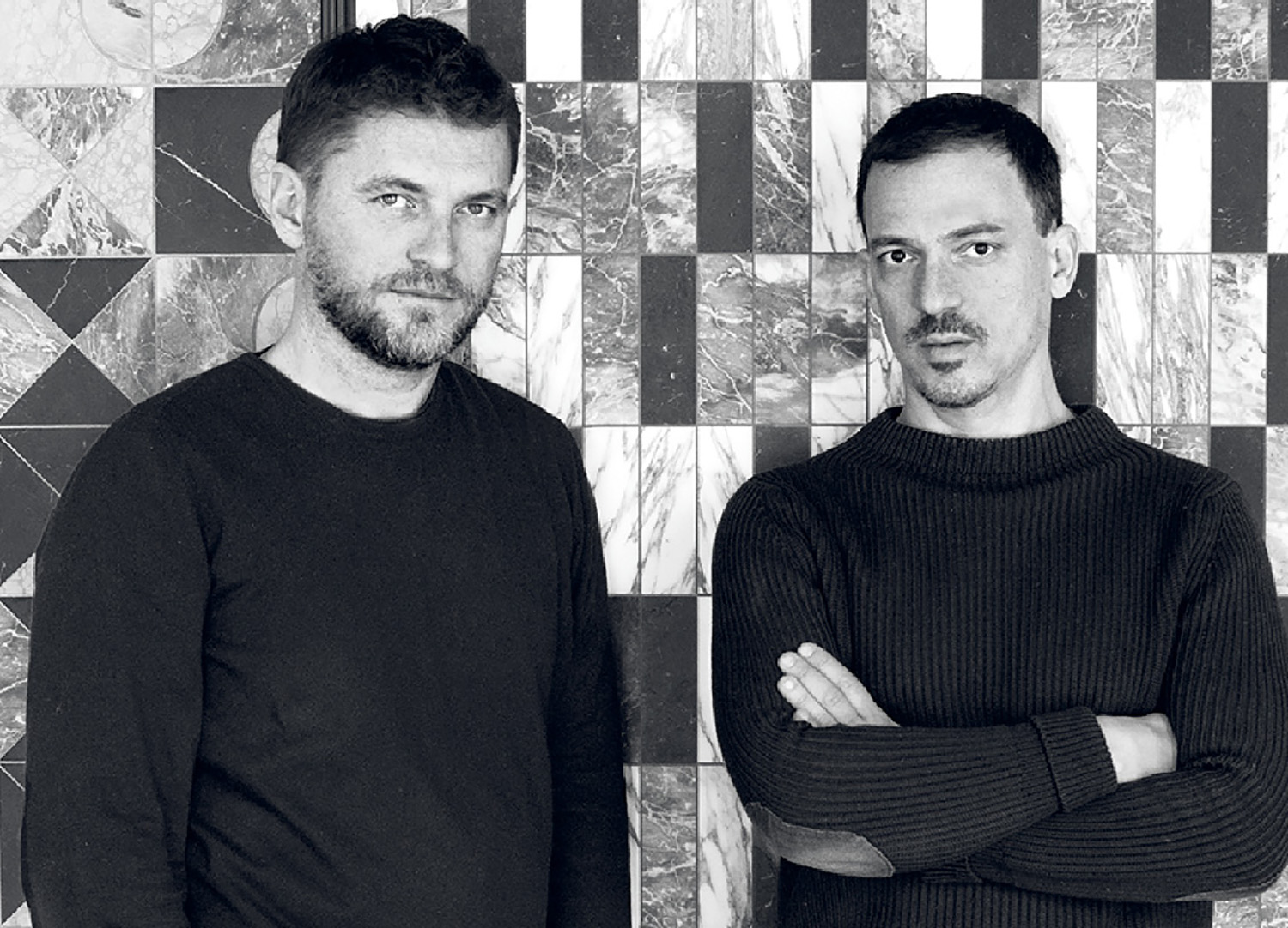 Two men standing in front of a wall