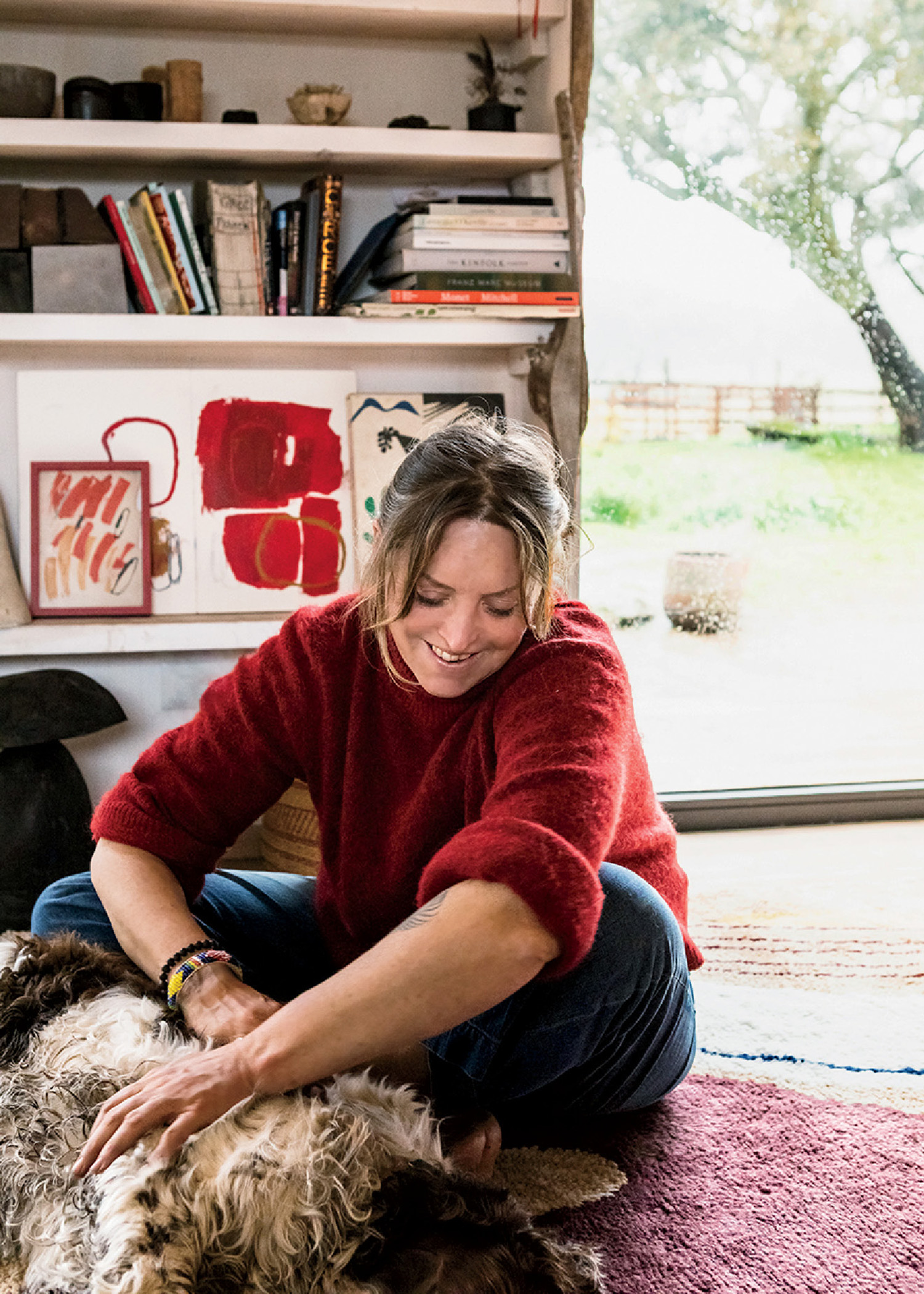 A woman sitting on a rug with a dog