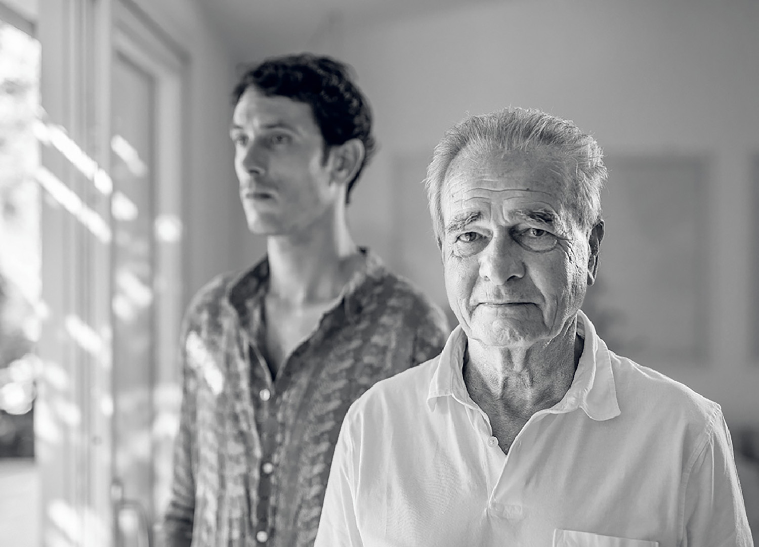 An older man and a young man standing in a hallway