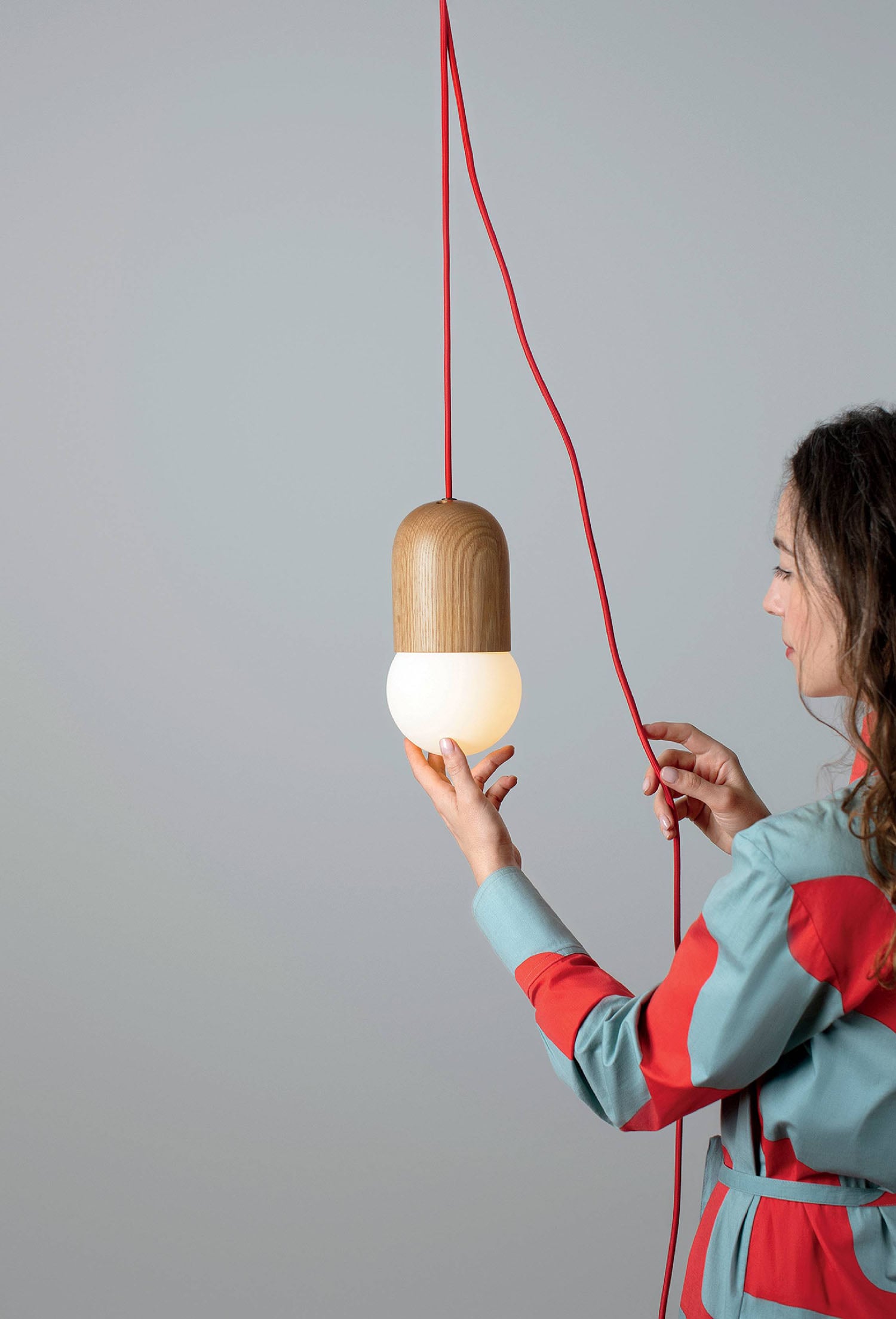 A woman holding a wooden light with a string.
