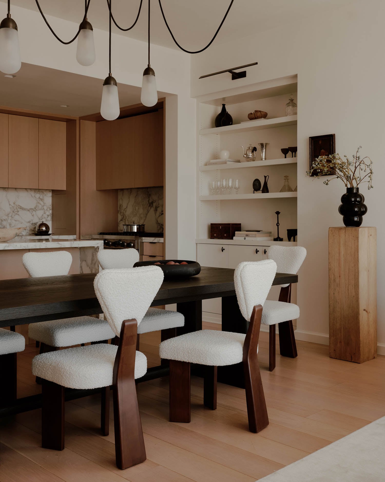 dining room with white chairs and hanging chandelier lights