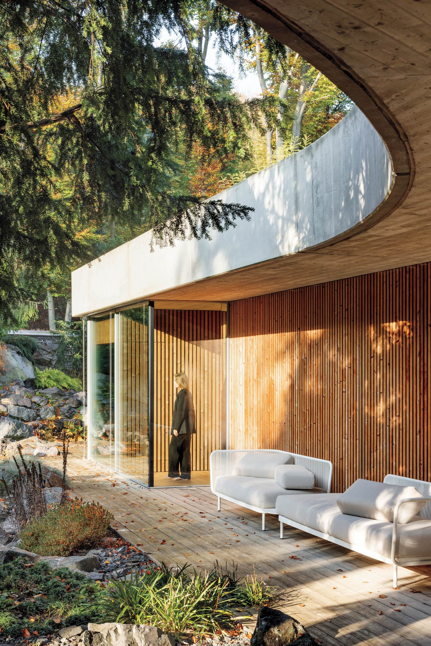 person standing outside home next to white chairs