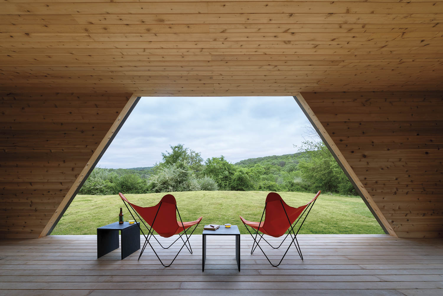two red chairs sitting on deck with view of the landscape