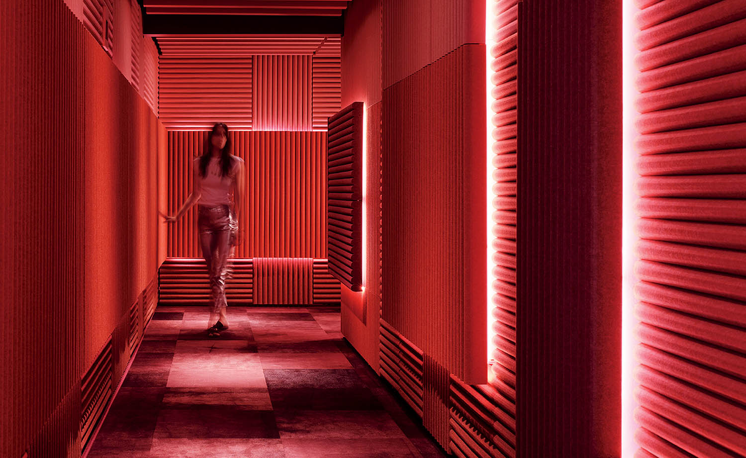 A woman walking down a hallway with red light.