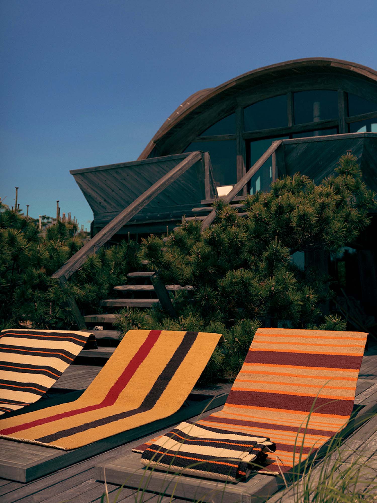 A row of striped beach chairs on a wooden deck.