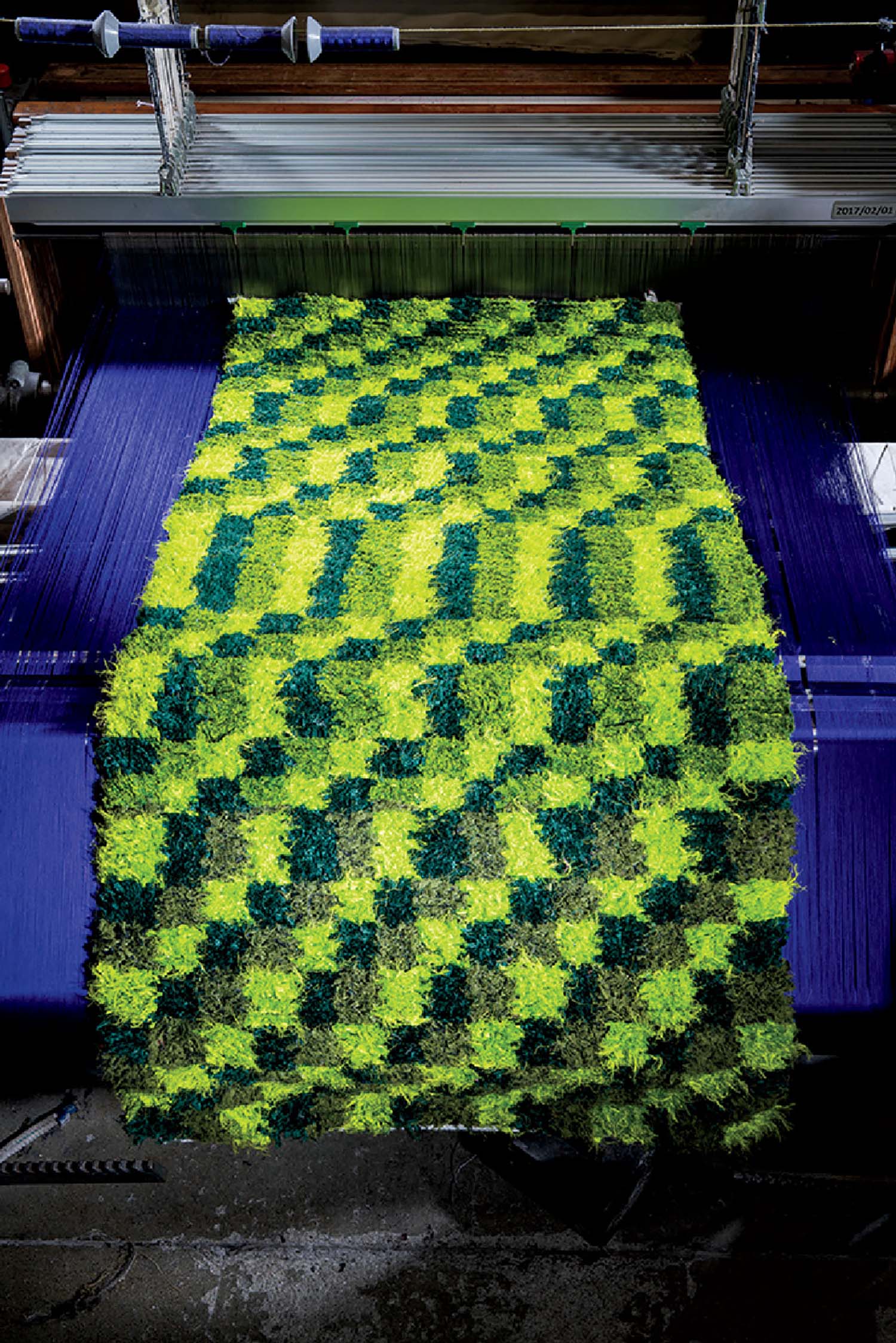 A green wall is being made from a machine.