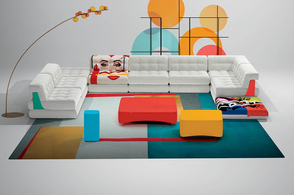 A living room with a large white couch and colorful rugs.