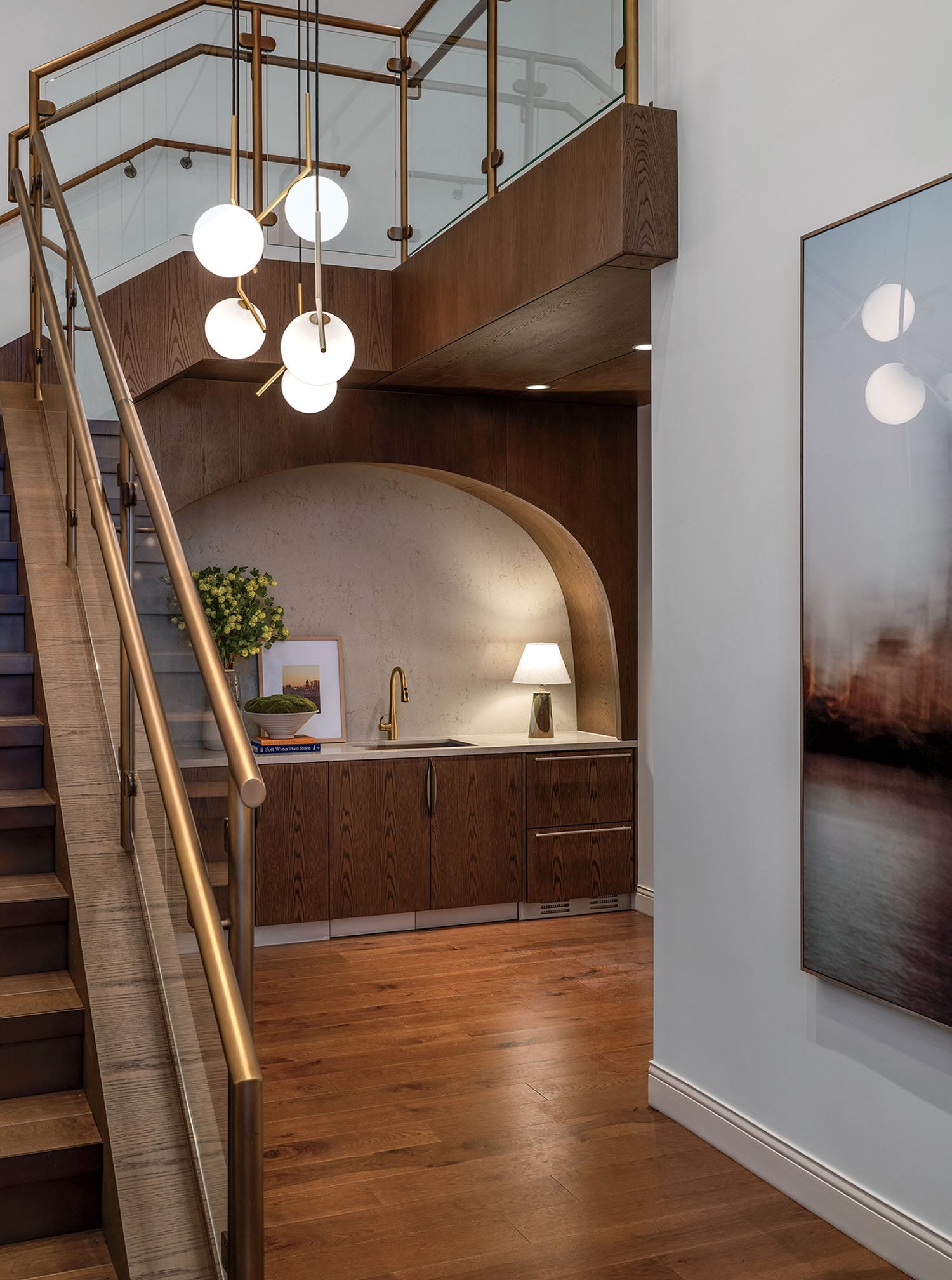 A staircase with a glass railing and a painting.
