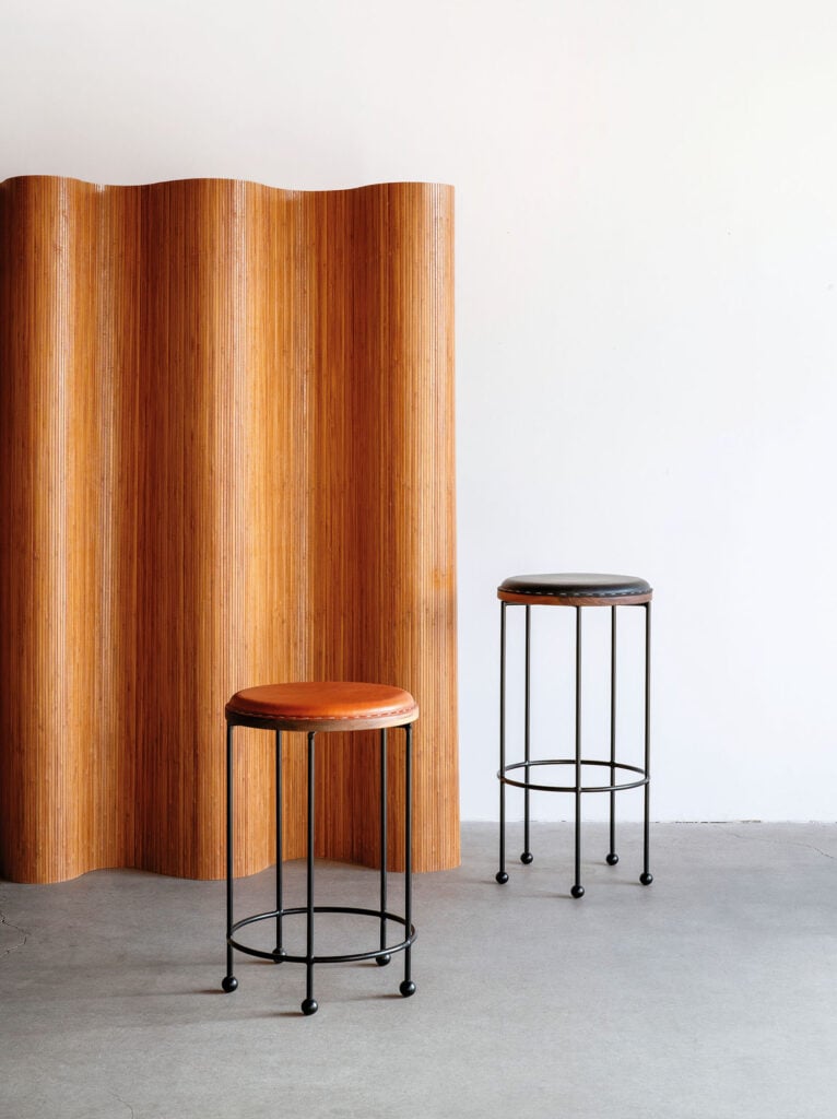 Two stools in front of a wooden wall.