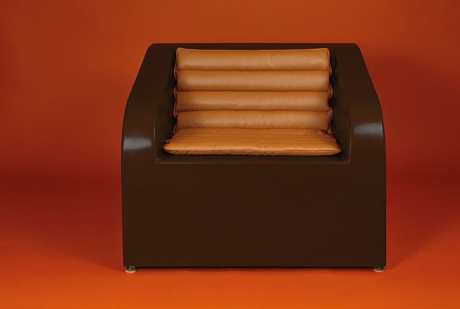 A brown leather chair with a pillow on it.