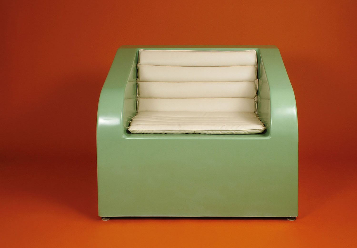 A green chair with a white pillow on it.