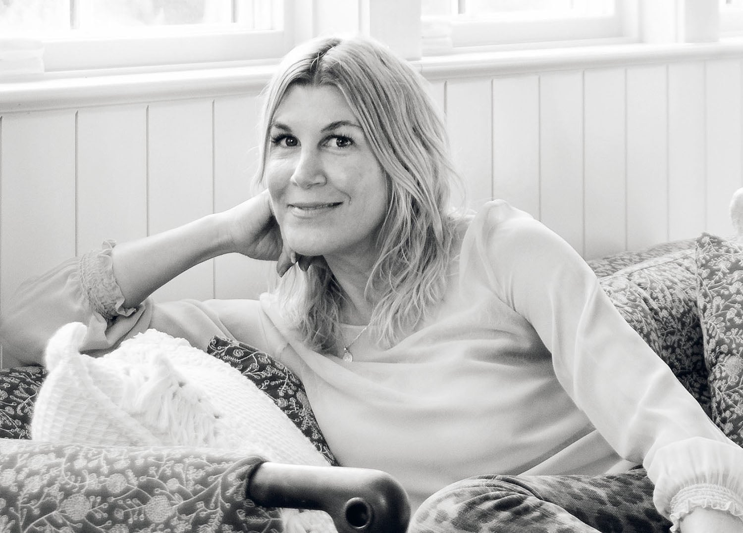 A woman sitting on a couch with her hand on her chin.