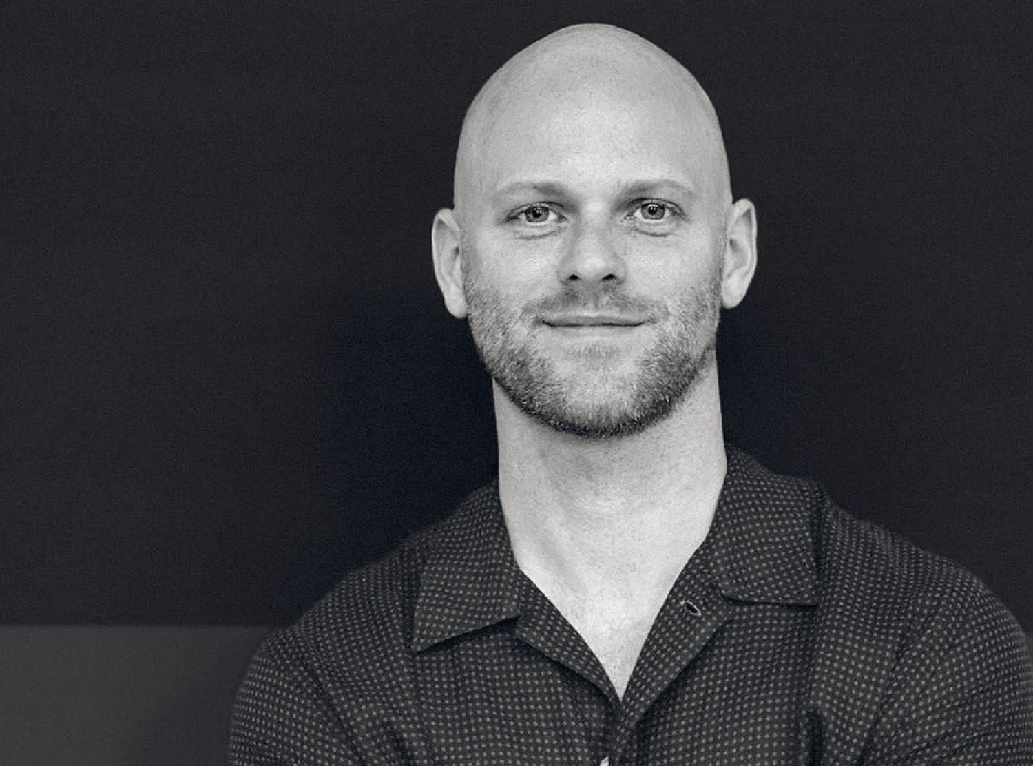 A man with a bald hair and a black shirt.