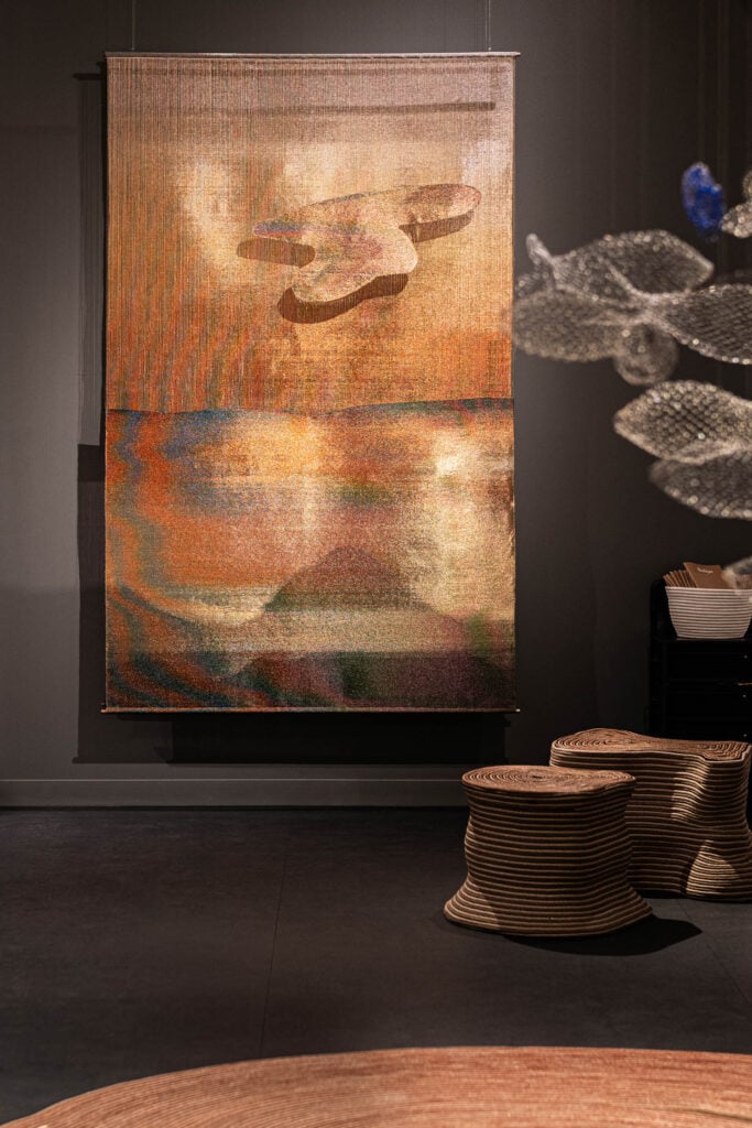 a weaving in rust orange on a dark gray wall