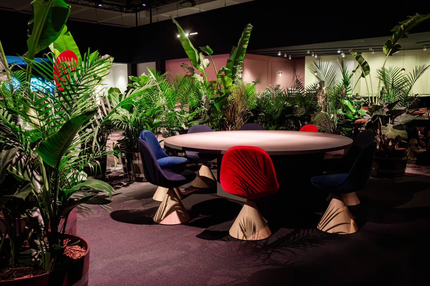 a moody lounge with tropical plants and red chair