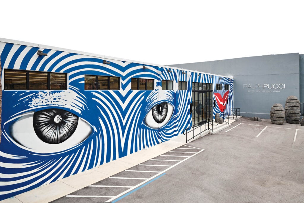 a wall mural with blue strips and eyes gazing out