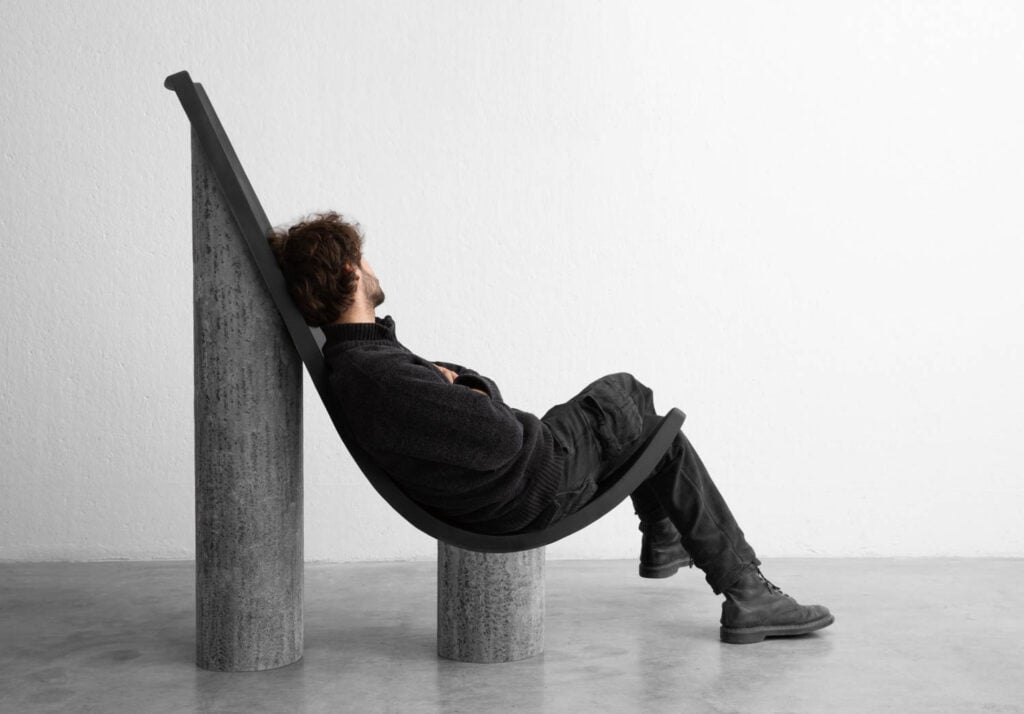 man in a black sling shaped chair