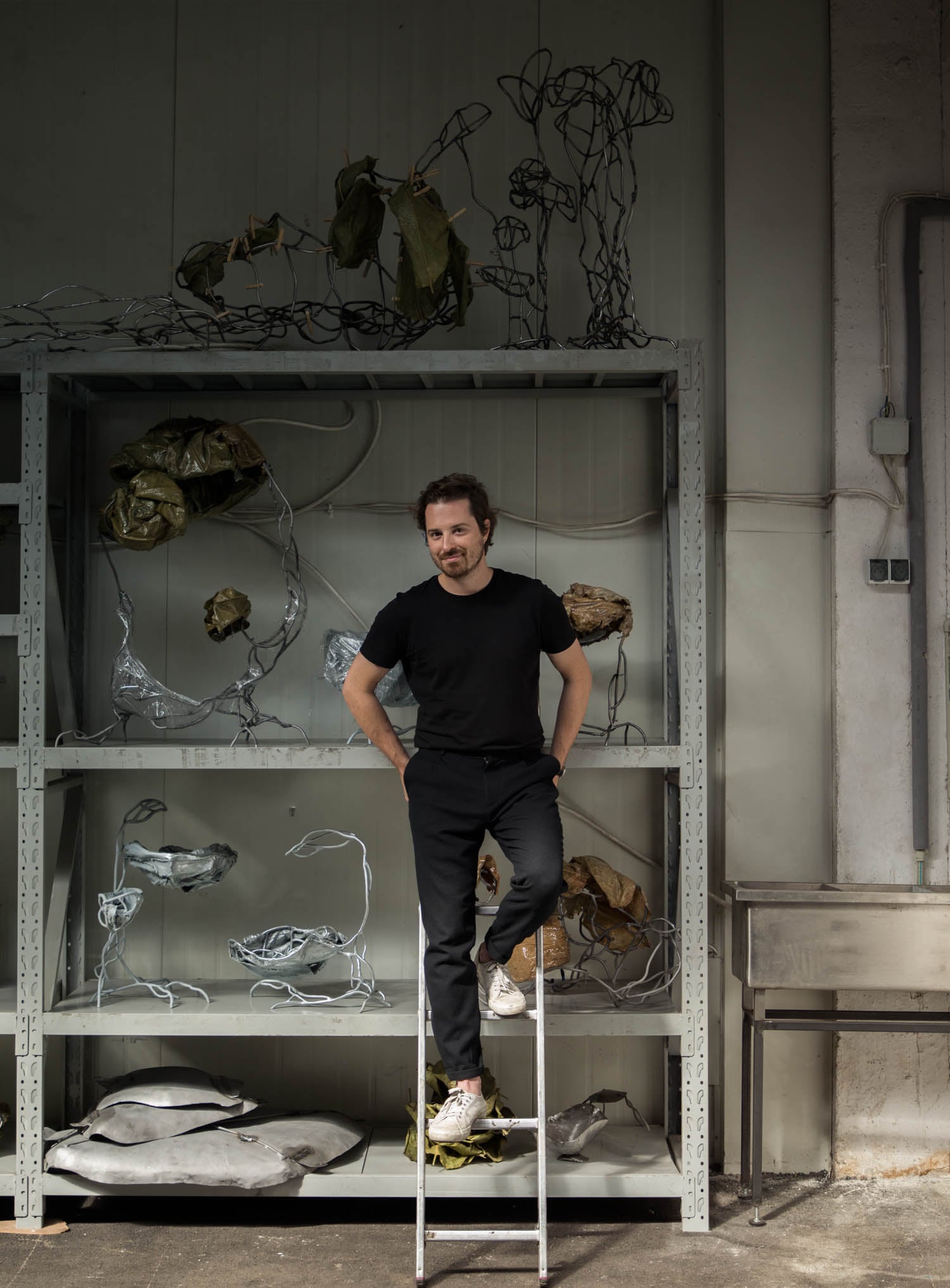 Marcin Rusak in a black t-shirt standing on a white ladder