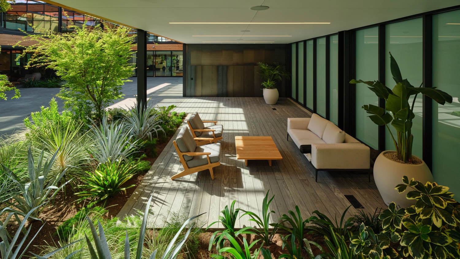 wooden deck sits outside the building with greenery