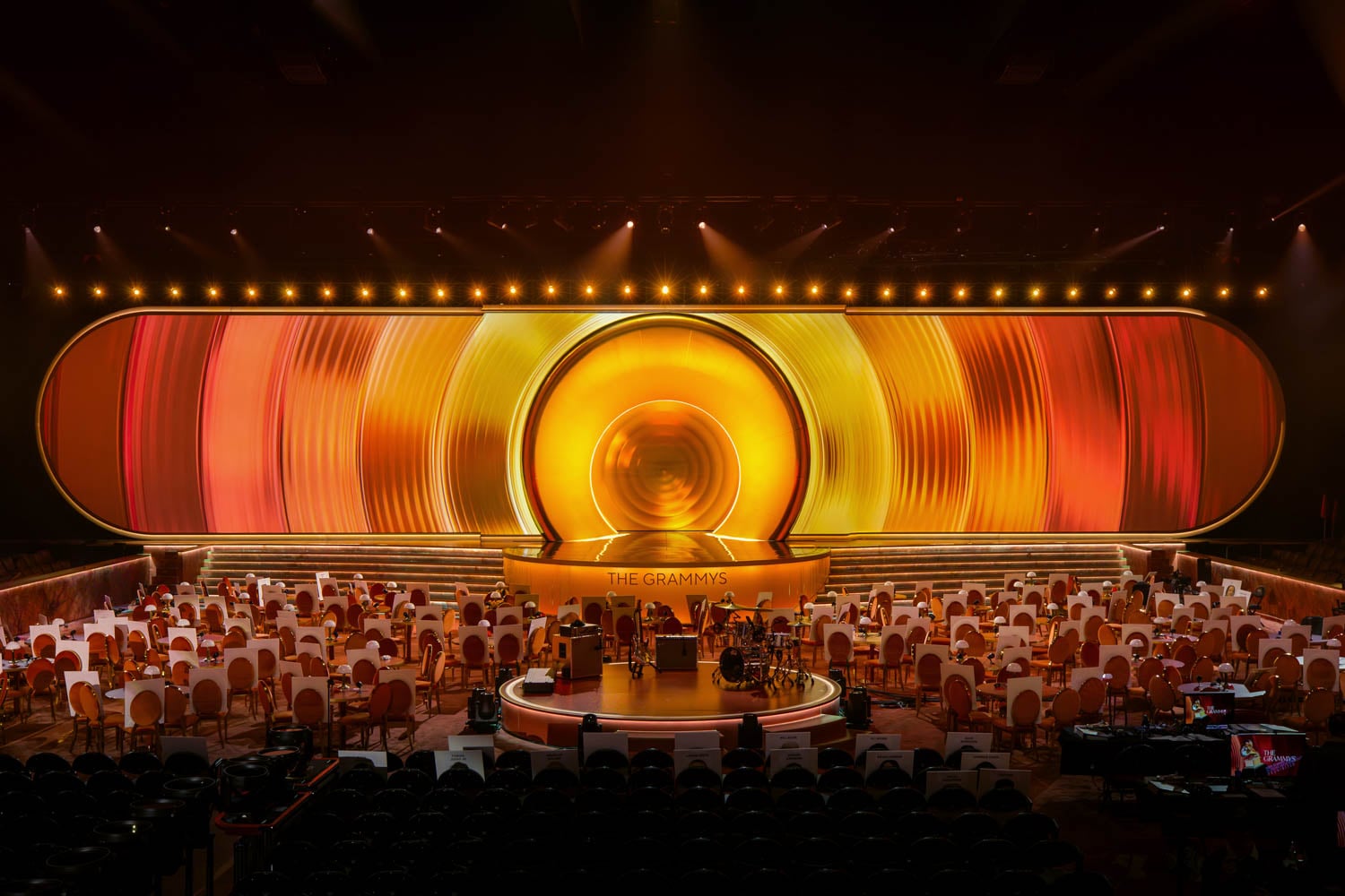 Grand stage setup for the Grammys with vibrant circular backdrop in warm hues of yellow, orange, and red.