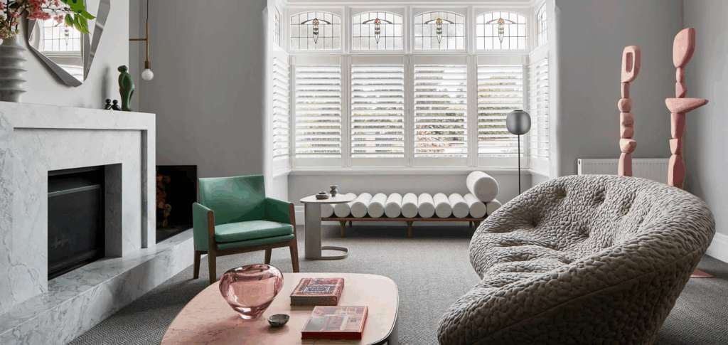 Stylish living room with a modern chandelier, marble fireplace, and large window with shutters