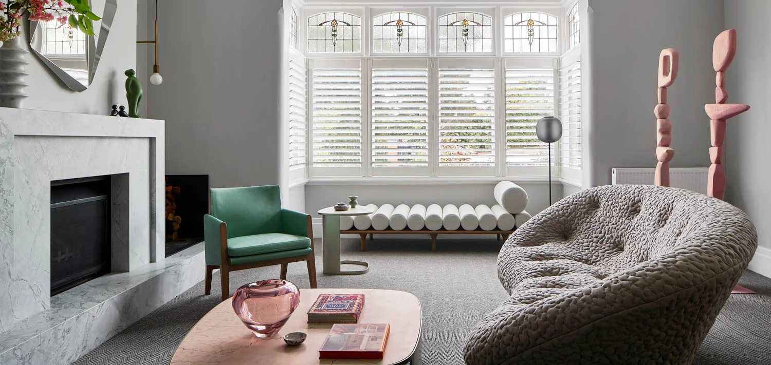 Stylish living room with a modern chandelier, marble fireplace, and large window with shutters