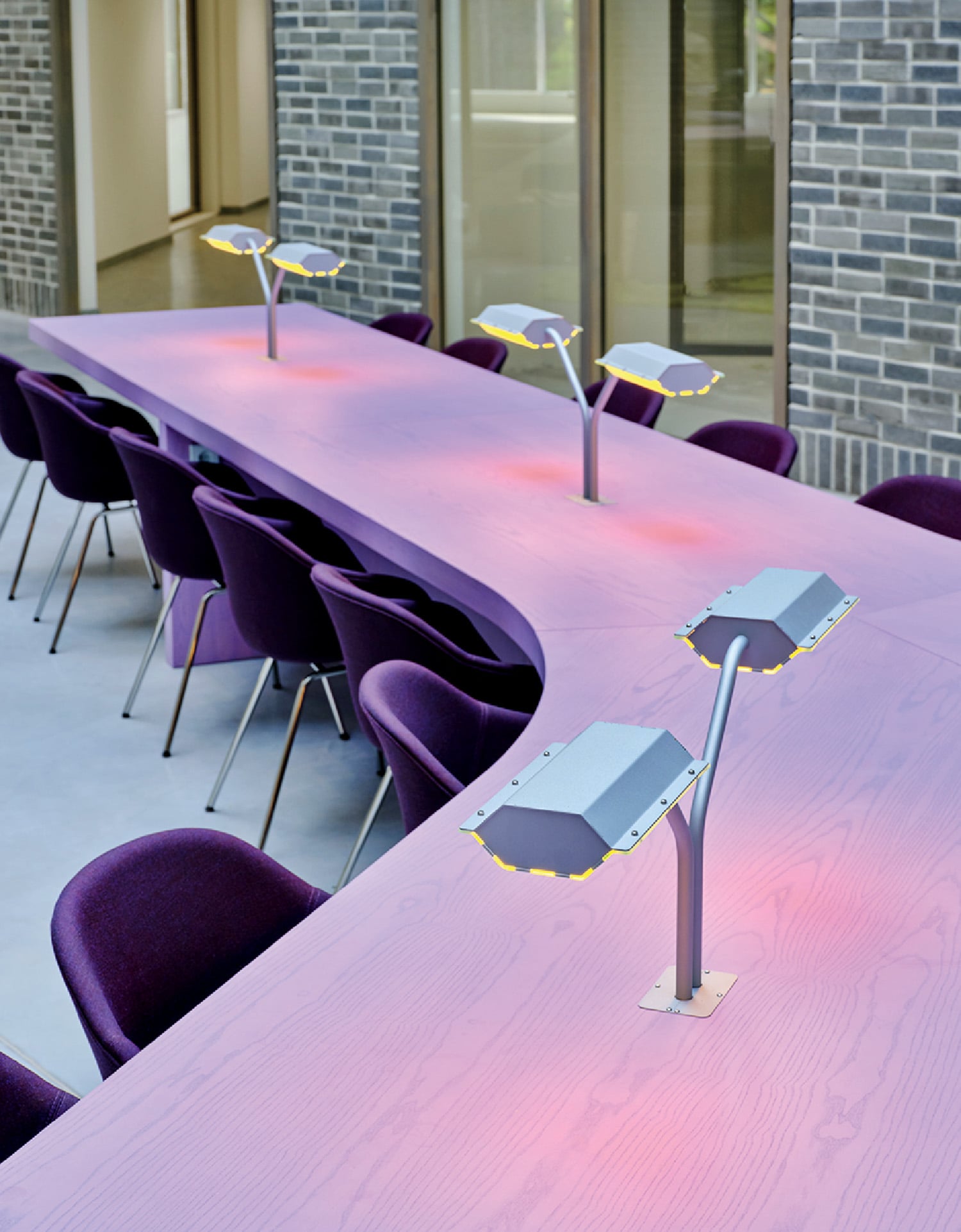 A long table with purple chairs and a light on it.