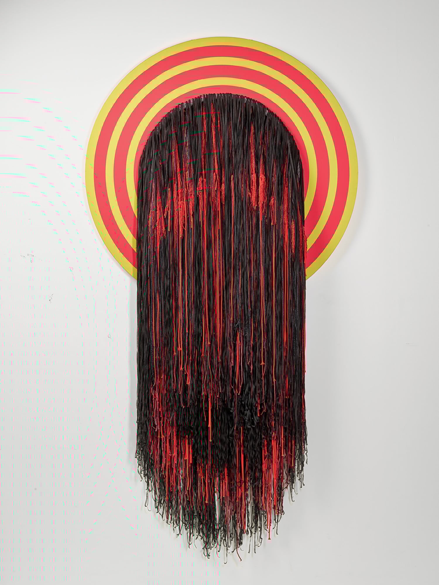 A red and yellow object with fringes hanging on the wall.