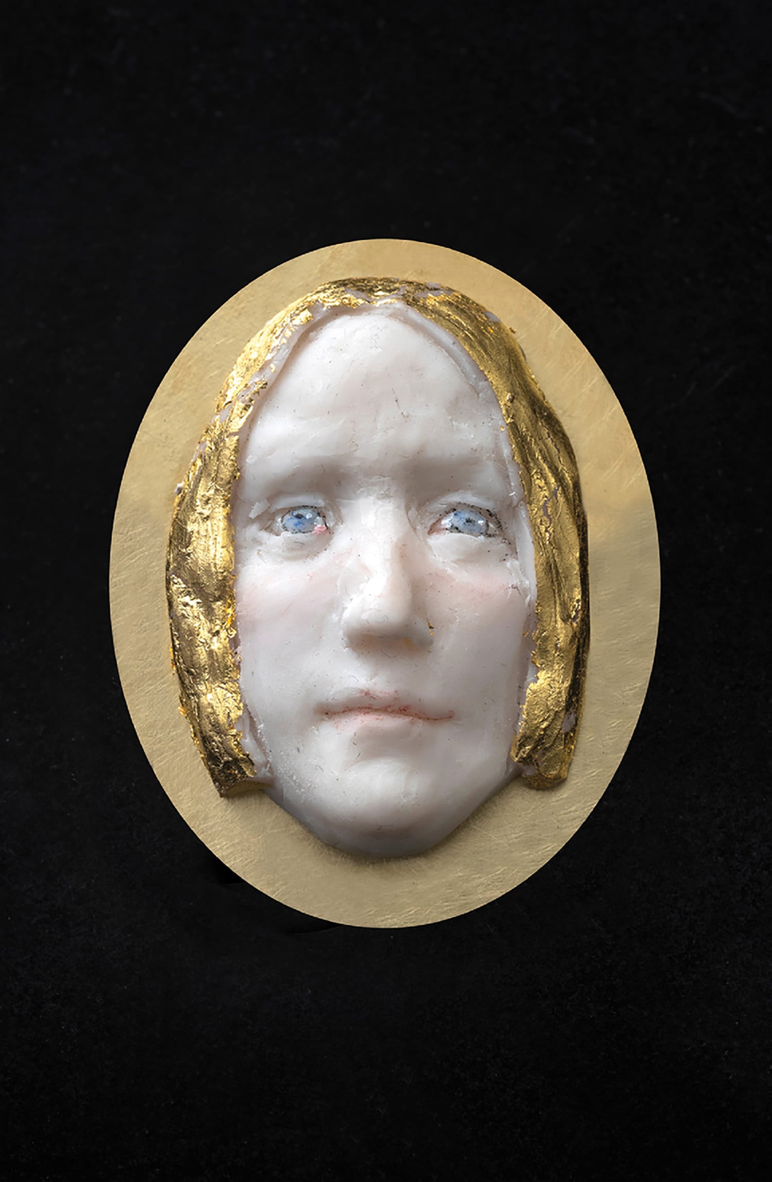 A close up of a face on a gold plate.
