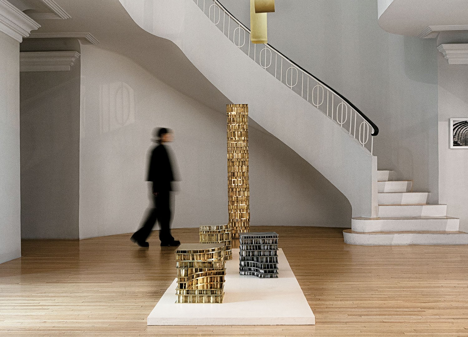 A man walking past a tall sculpture in a room.