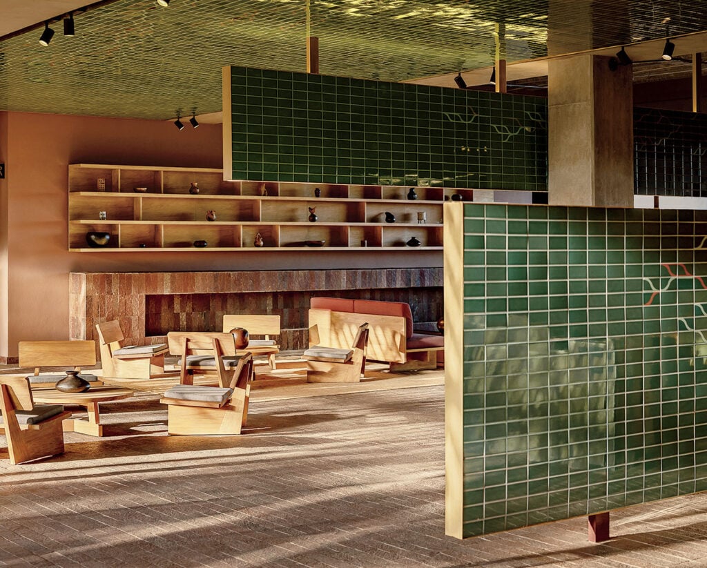 A room with a fireplace and a green tiled wall.