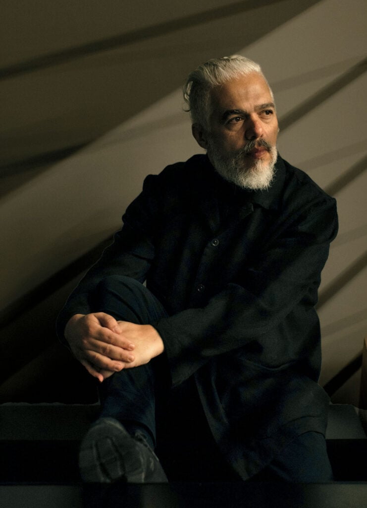 A man sitting on a bench with his hands folded.