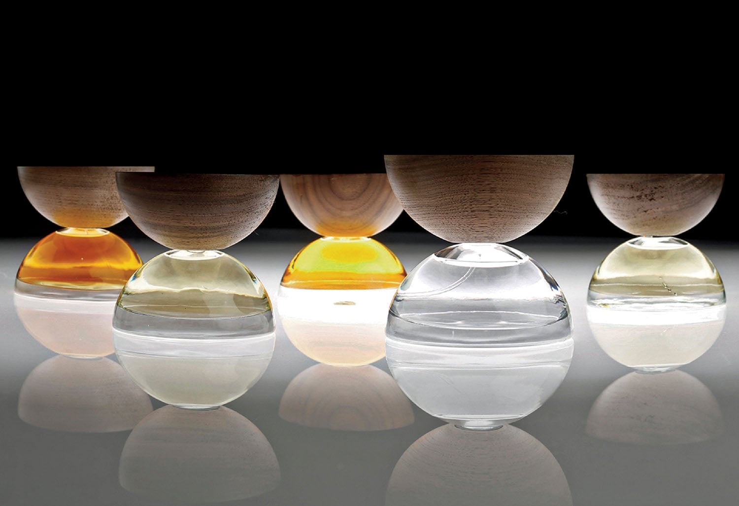 A row of glass vases on a reflective surface.