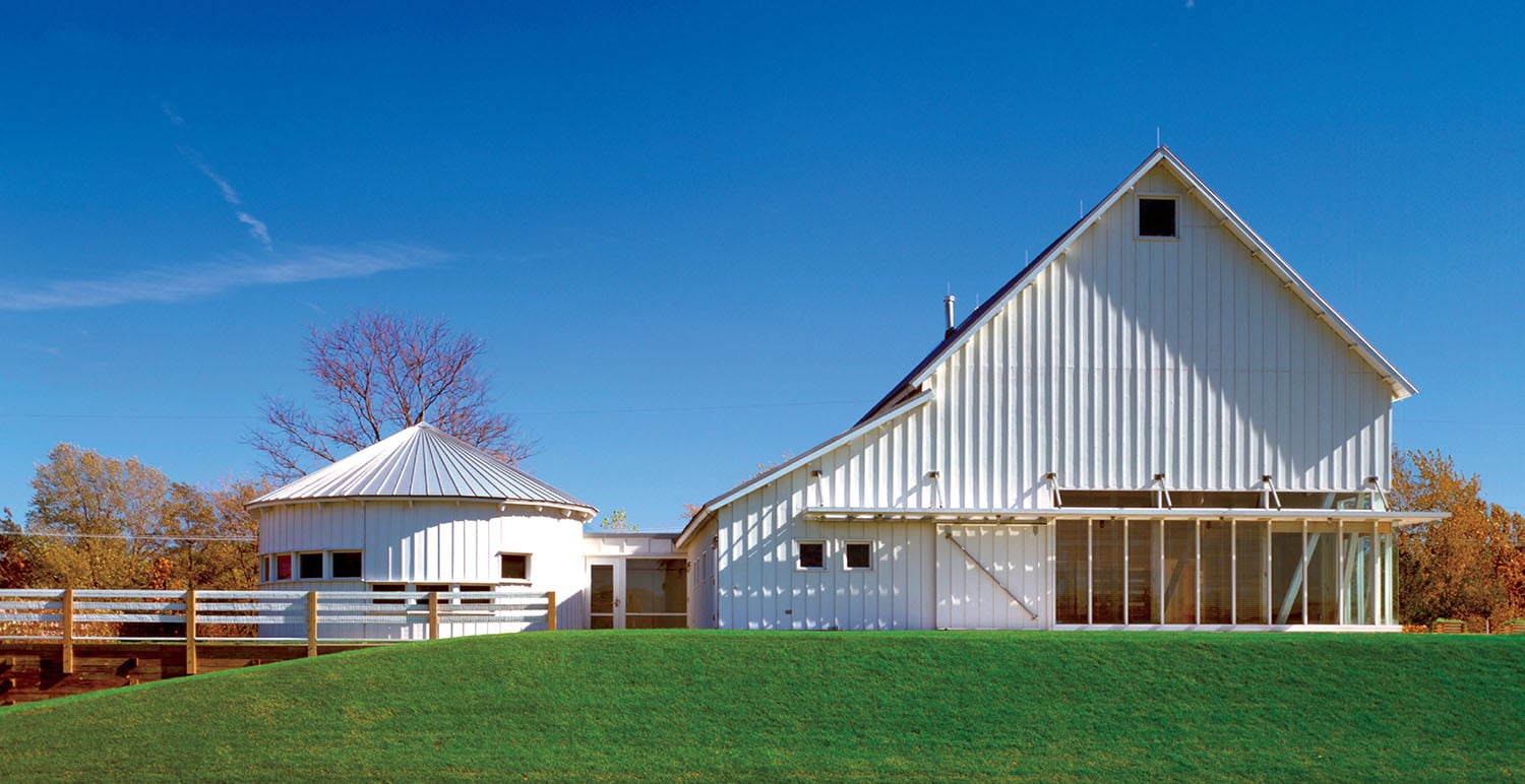A white barn with a white fence and a white barn with a white ro.