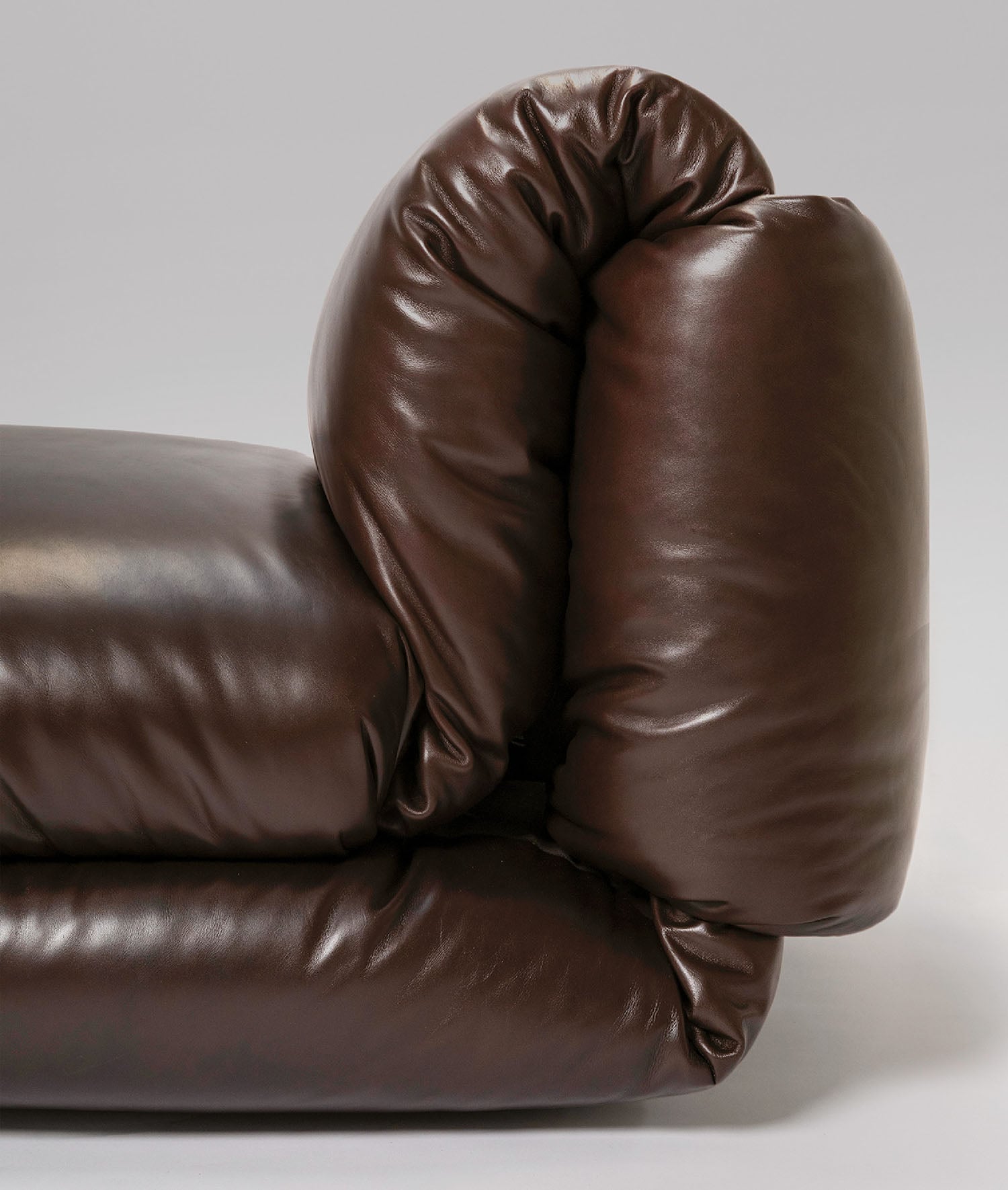 A brown leather couch with a pillow on it.