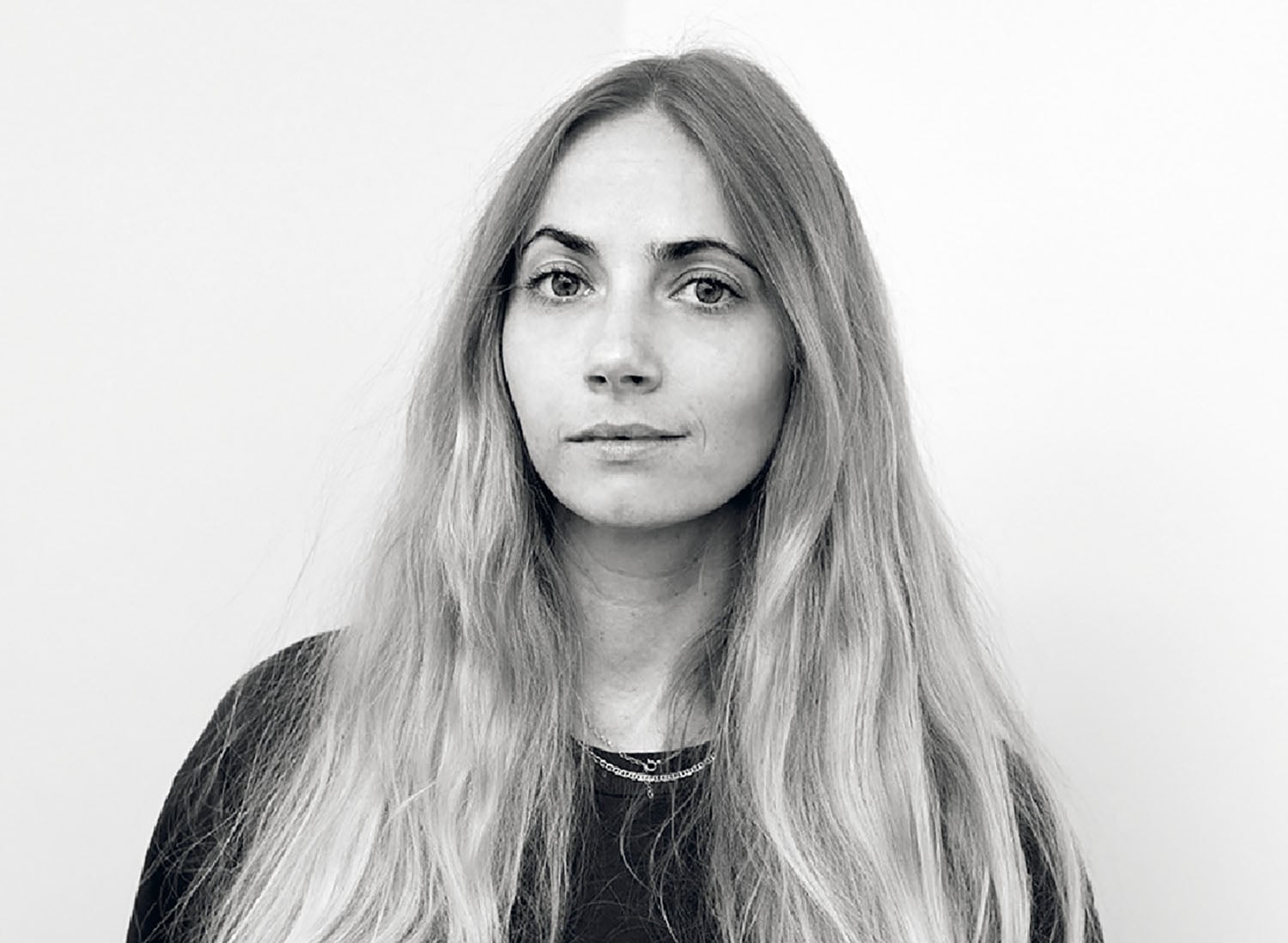 A woman with long blonde hair and black shirt.