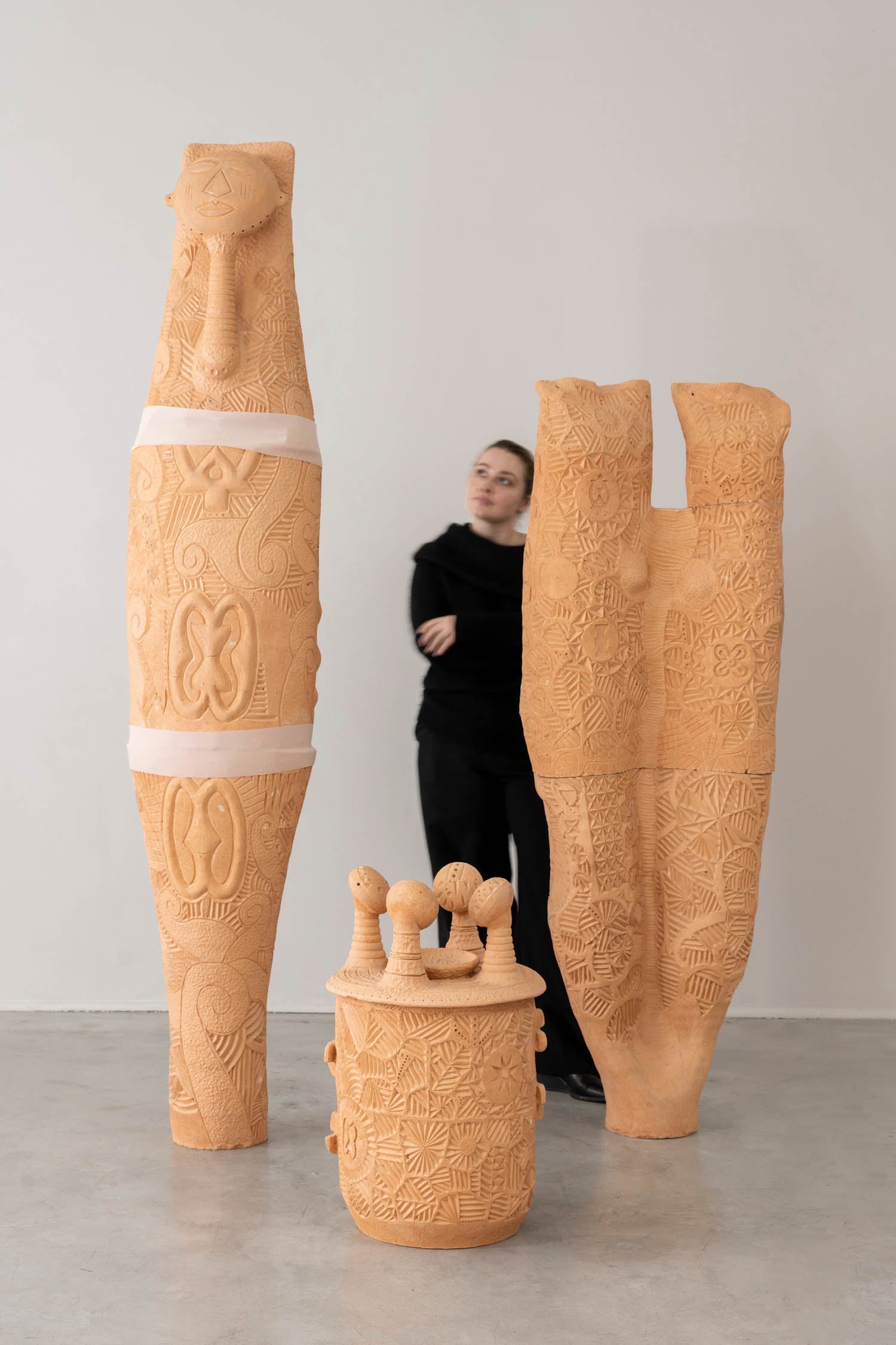 woman standing next to tan sculptures